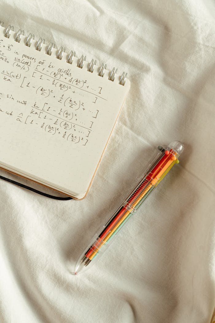 Handwritten math formulas on a notepad with a colorful pen on a white background.